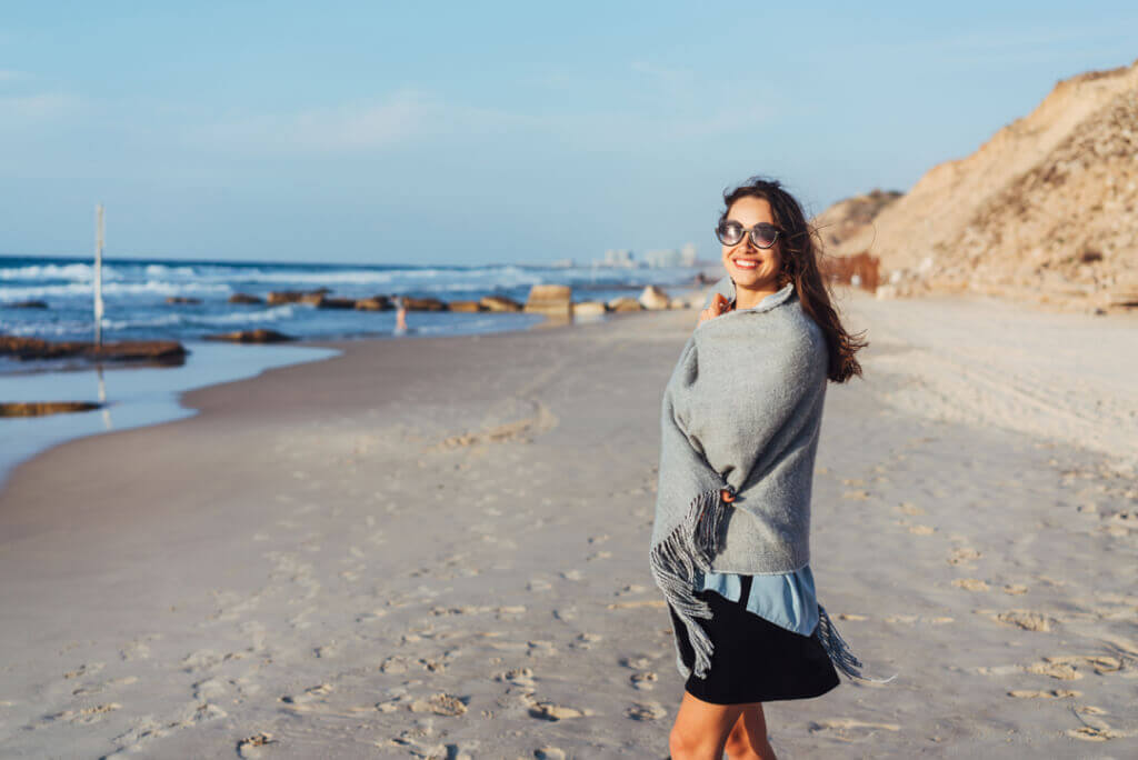 cocaine addiction treatment woman at beach sand smiling glasses rocks
