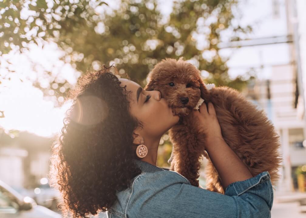 young woman kissing puppy dog pets emotional support wellness mental health rehab friendly