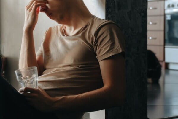 dealing anxiety exhausted upset depressed young millennial man cuddling with pet cat loss grief trauma sit on floor covid symptoms