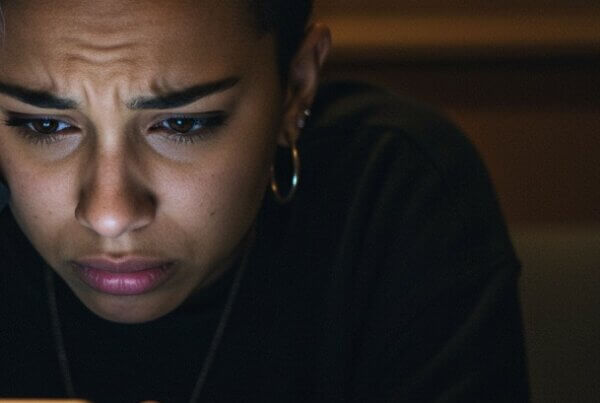 Stressed Gen Z teen on a mobile phone searching for information on 30-day rehab options.